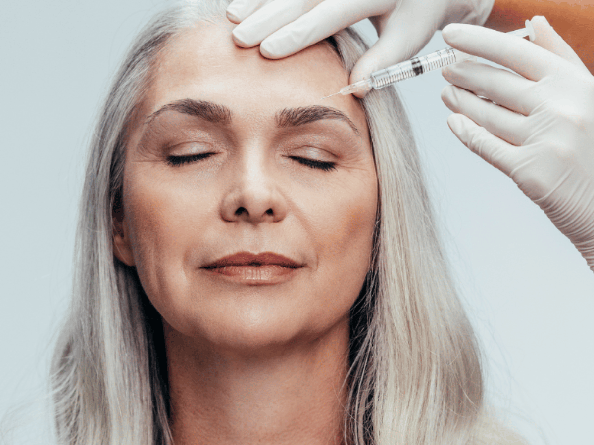 A middle aged woman getting an injectable in her forehead.